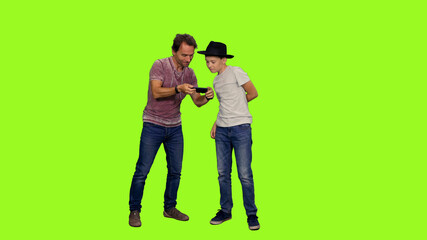 Father takes a picture of his little son with smartphone and showing on green screen chroma key background,