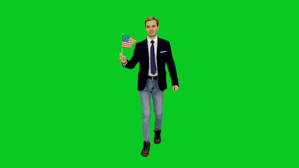 Young happy man in santa hat walking with waving flag of USA against green screen background, Front view, Full body chroma key
