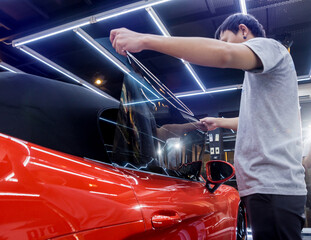Applying tinting foil on a car window in a auto service