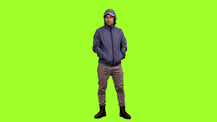 Front view of hooded man standing with hands in pockets on green background, Chroma key