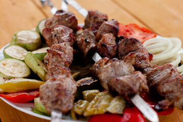 a tray with meat on skewers sprinkled with herbs on grilled vegetables