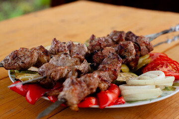a tray with meat on skewers sprinkled with herbs on grilled vegetables