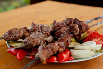 a tray with meat on skewers sprinkled with herbs on grilled vegetables