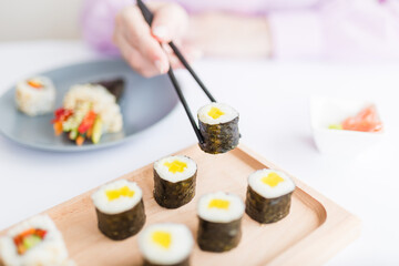 Woman hand taking piece of sushi roll with chopsticks. Healthy seafood asian japanese dish.