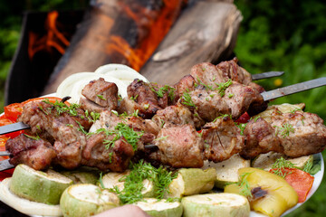 a tray with meat on skewers sprinkled with herbs on grilled vegetables