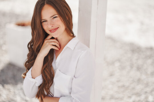 Pretty woman on the beach at summer white shirt and denim shorts wooden background sitting 