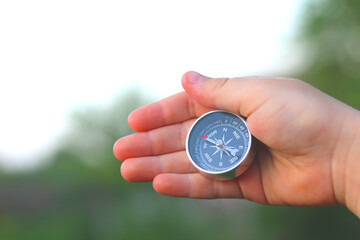 Old classic navigation compass in hand on natural background as symbol of tourism with compass,...