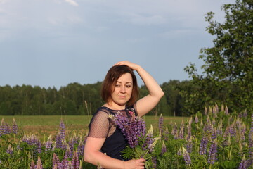 young pretty girl on a field with lupine flowers