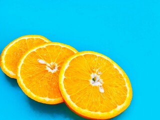 Fresh orange slices on blue background closeup. Flat lay, copyspace, top view.