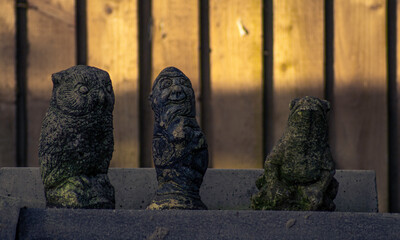 Stone Figures In Front Of Wooden Fence In England