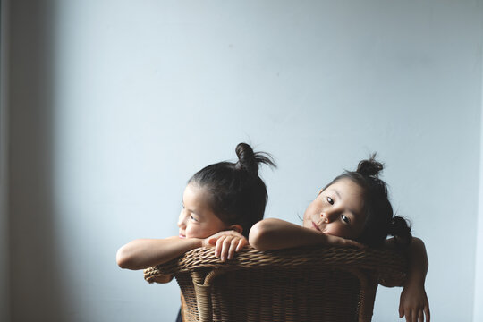Sisters leaning on chair at home