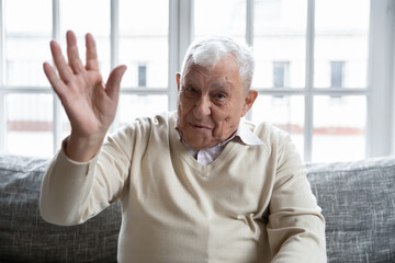 Head shot portrait happy mature man waving hand, saying hello, looking at camera, friendly older...