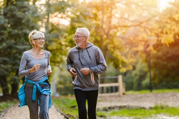 Tuinposter Smiling senior couple jogging in the park © lordn