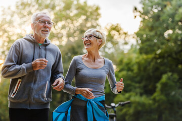 Smiling senior couple jogging in the park - Powered by Adobe