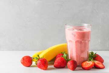 Glass of strawberry and banana smoothie or milkshake with fresh fruits and berries. refreshing summer drink