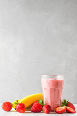 Glass of strawberry and banana smoothie or milkshake with fresh fruits and berries. refreshing summer drink. vertical orientation