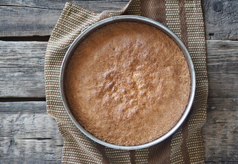 The process of making a banana biscuit. Ready-made biscuit in a baking dish cools down on a wooden ancient table. Confectionery background.