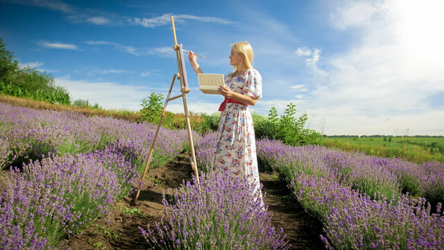 Young woman drawing picture of beautiful lavender field in Provence