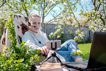 Remote work and at home in the garden. The girl works on a laptop in the garden conference, a...