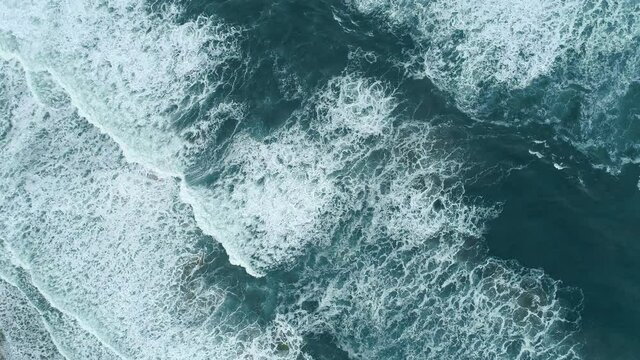 Turquoise waters of great ocean. Whitecaps rolling the surface during light storm. Aerial top down shot, UHD