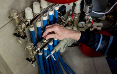 Heating engineer fixing modern heating system in boiler room. 
