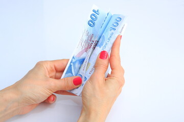 Turkish banknote view in female hand on white background.