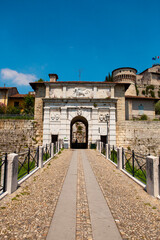 Close up. The entrance of the medieval fortress with the lion sculpture. The castle has towers, a trench, a bridge made of white marble stones (bricks) in an Italian city - Brescia, Lombardy, Italy