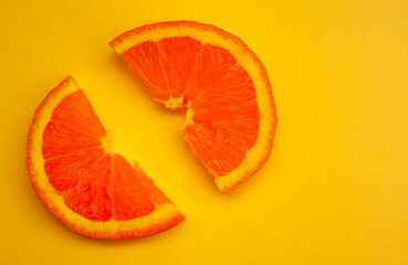 two slices of orange on a yellow background top view.