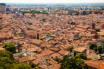 Aerial view of the historical center of Brescia (Lombardy, Italy) with tiled red roofs, chimneys, cathedral's domes and tall white brick old towers. Traditional European medieval architecture. 