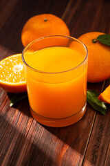 Obraz na płótnie Canvas Fresh orange juice in glass and oranges fruit on wooden table background.