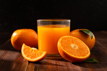 Fresh orange juice in glass and oranges fruit on wooden table background.
