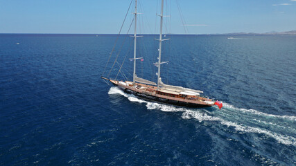 Fototapeta premium Aerial drone photo of beautiful sail boat with wooden deck sailing the Aegean deep blue sea, Greece