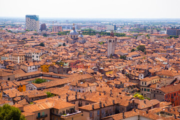 Fototapeta na wymiar Aerial view of the historical center of Brescia (Lombardy, Italy) with tiled red roofs, chimneys, cathedral's domes and tall white brick old towers. Traditional European medieval architecture. 