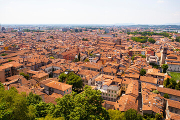 Aerial view of the historical center of Brescia (Lombardy, Italy) with tiled red roofs, chimneys, cathedral's domes and tall white brick old towers. Traditional European medieval architecture. 