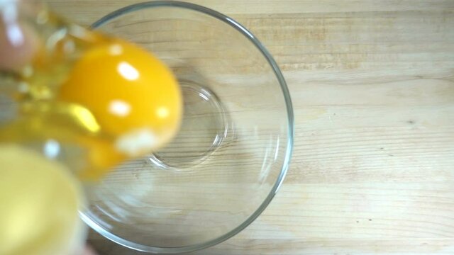 Raw egg falls in slow motion into a transparent bowl.