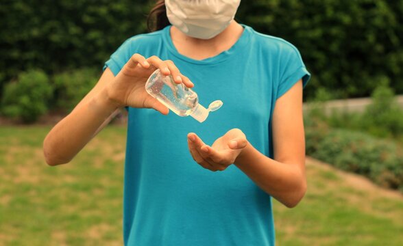 Young Woman Using A Desinfectant Gel To Sanitize Her Hands In Order To Prevent Getting Ill 