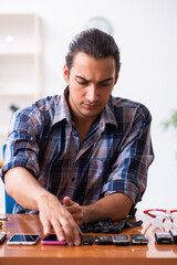 Young male technician repairing mobile phone