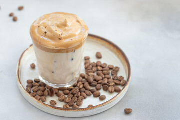 cold Dalgona coffee with whipped cream in a glass on a background of coffee beans. summer ice drinks. close-up. horizontal image. copy space