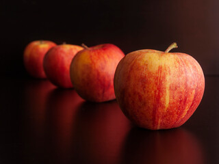 Red apples forming a row in perspective, on a dark background, shallow depth of field