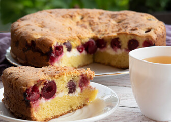 A piece of cherry pie with a Cup of tea.