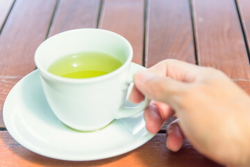 The man hold the hot green tea on his hand before drink / hot matcha
