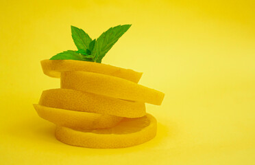 Naklejka na ściany i meble lemon and mint on a yellow background. slices of lemon lie on top of each other, on the topmost piece are mint leaves.