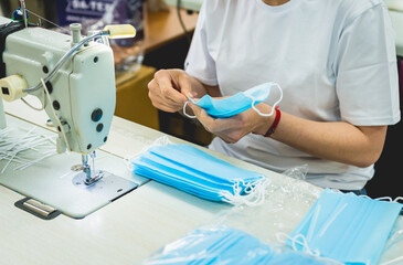 Woman sew the facial medical at sewing machine. Coronavirus pandemia.