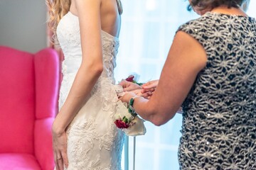 Closeup shot of bridesmaid is helping the bride to dress