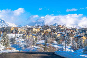 Sunlit town with homes on snowy Wasatch Mountain terrain on a sunny winter day