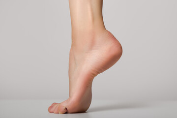 Female foot. Heel. Stability of the foot on a gray background. Neat foot. feet care