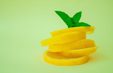 sliced ​​lemon and mint on a light green background. a pyramid of cut lemon slices with mint leaves at the top.
