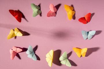 origami butterflies in circle on lilac background, shadows, copy space 
