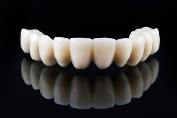 dental upper jaw prosthesis without gums on a black background with reflection