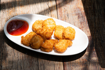 chicken nugget fry on white round ceramic plate with pepper half ketchup source on wood table stock photo